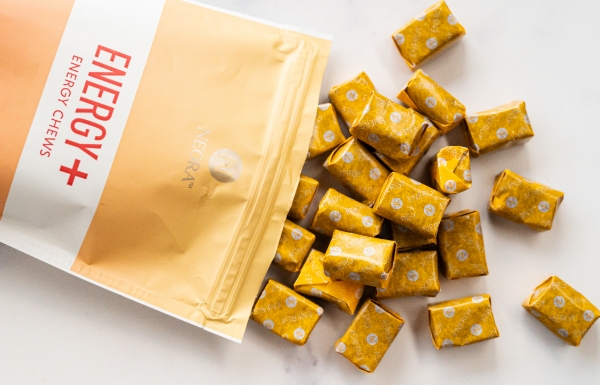 Lifestyle shot of Energy+ Wellness Chews spilling out of the bag on a white table.